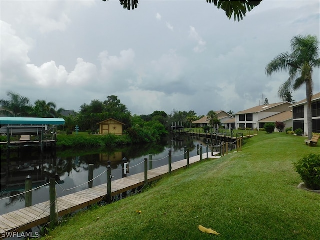 surrounding community with a water view, a lawn, and a dock