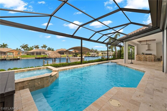 view of swimming pool featuring an outdoor bar, a water view, glass enclosure, a patio area, and an in ground hot tub