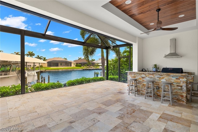 exterior space featuring a water view, ceiling fan, exterior bar, and a patio