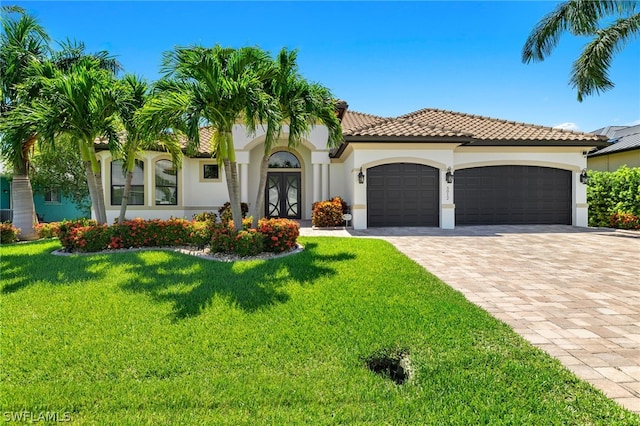 mediterranean / spanish-style house with a garage, a front yard, and french doors