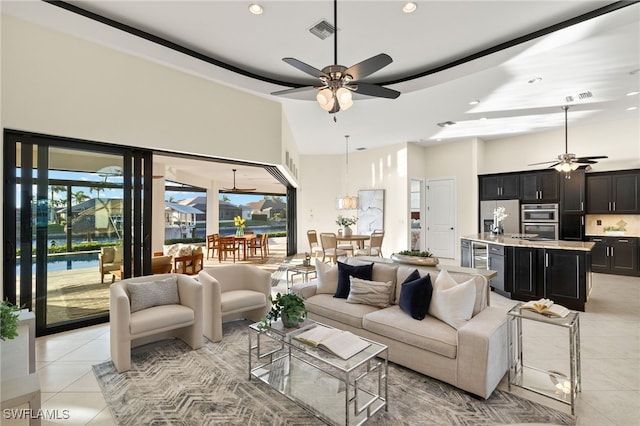 living room with light tile patterned floors, a towering ceiling, and ceiling fan