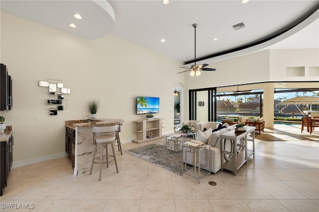 living room featuring a high ceiling, sink, light tile patterned floors, and ceiling fan