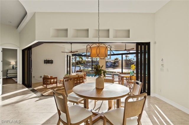 tiled dining space featuring ceiling fan and a towering ceiling