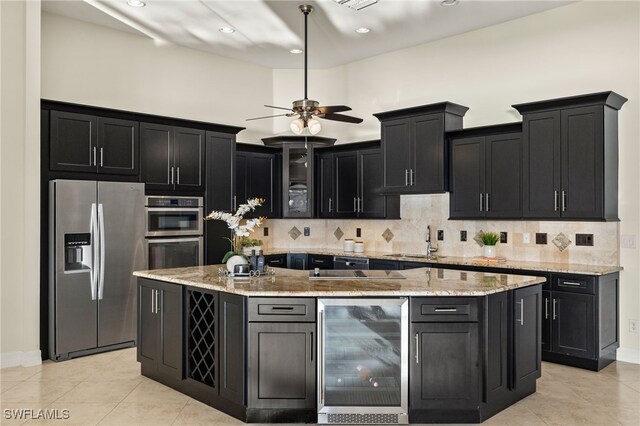 kitchen with tasteful backsplash, sink, beverage cooler, a kitchen island with sink, and stainless steel appliances