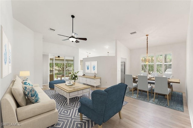 living room with ceiling fan with notable chandelier, wood finished floors, visible vents, and baseboards
