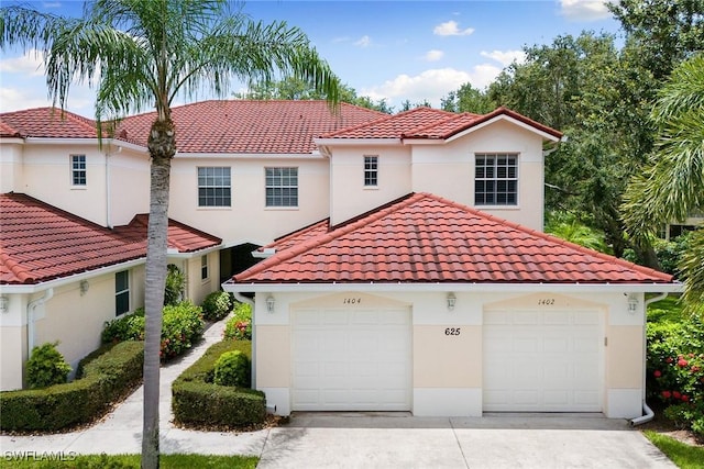 mediterranean / spanish house featuring a tiled roof, a garage, and stucco siding