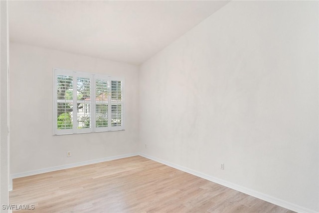 spare room with baseboards and light wood-style floors