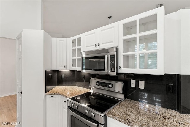 kitchen with decorative backsplash, white cabinets, glass insert cabinets, and appliances with stainless steel finishes