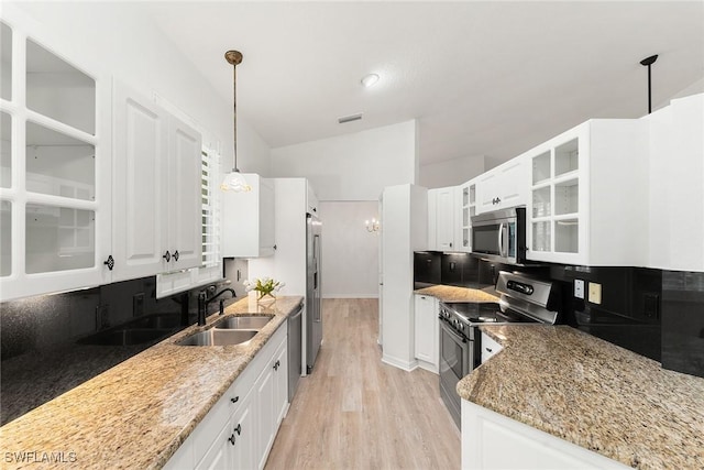 kitchen featuring tasteful backsplash, light stone counters, appliances with stainless steel finishes, white cabinets, and a sink
