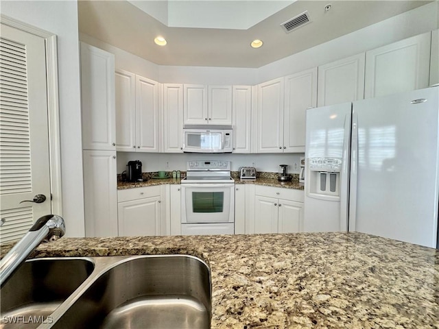 kitchen with white cabinets, white appliances, sink, and dark stone counters