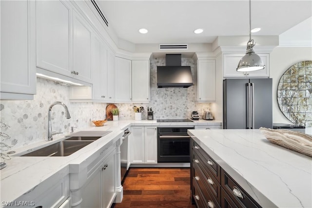 kitchen with decorative light fixtures, white cabinetry, sink, black appliances, and wall chimney exhaust hood