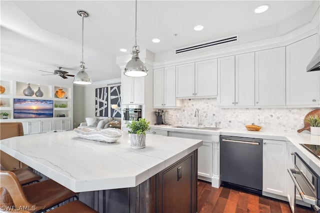 kitchen with sink, decorative light fixtures, appliances with stainless steel finishes, a kitchen island, and white cabinets