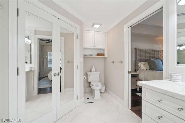 bathroom featuring french doors, crown molding, vanity, and toilet