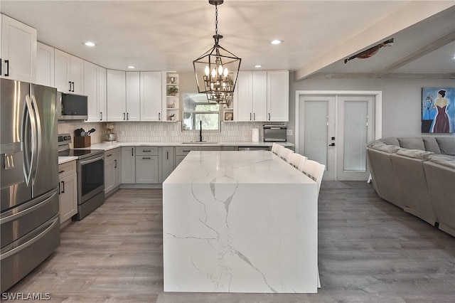 kitchen featuring wood-type flooring, stainless steel appliances, sink, a kitchen island, and backsplash