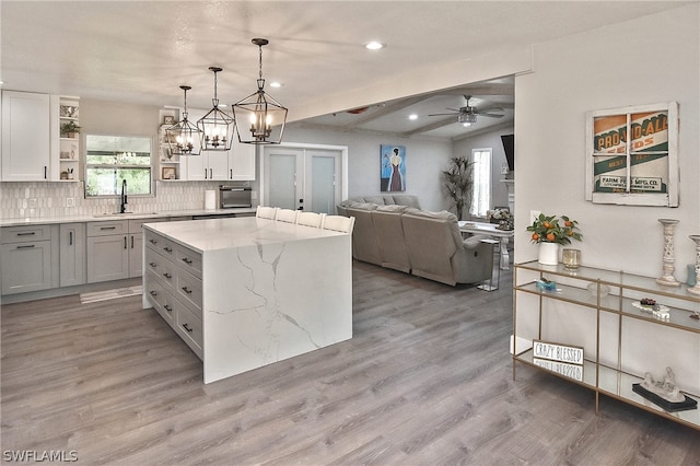 kitchen featuring ceiling fan with notable chandelier, a center island, hardwood / wood-style floors, and pendant lighting