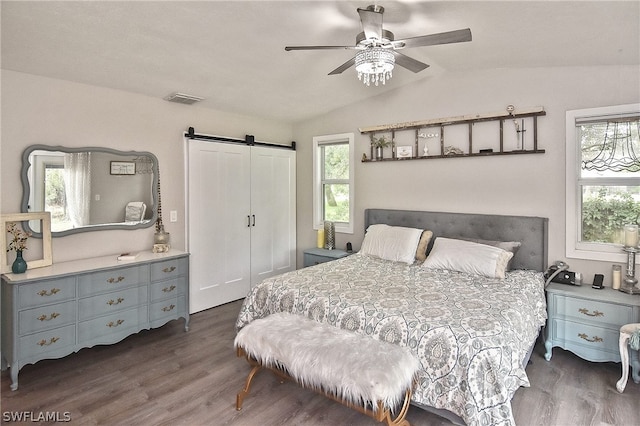 bedroom with a barn door, lofted ceiling, ceiling fan, and dark wood-type flooring