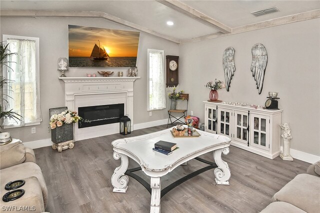 living room with lofted ceiling with beams, wood-type flooring, and a wealth of natural light