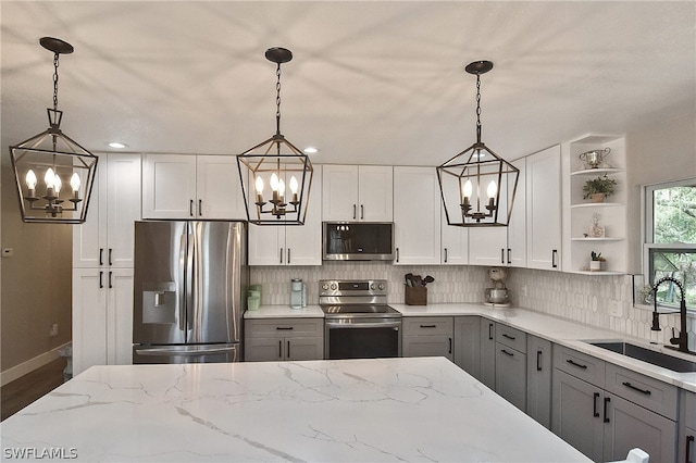 kitchen with sink, appliances with stainless steel finishes, pendant lighting, and gray cabinets