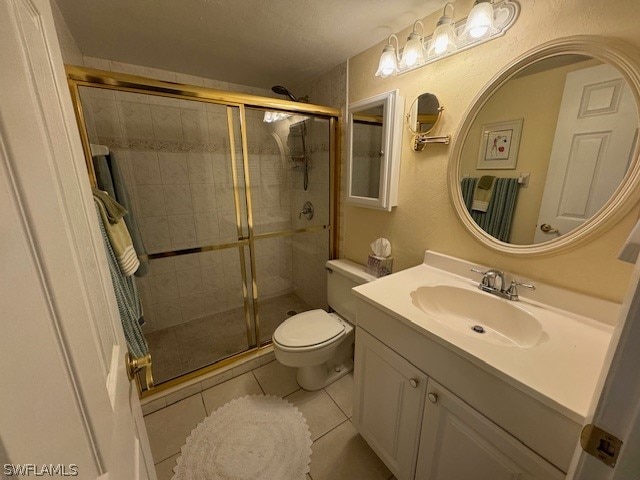 bathroom featuring tile patterned flooring, vanity, toilet, and an enclosed shower