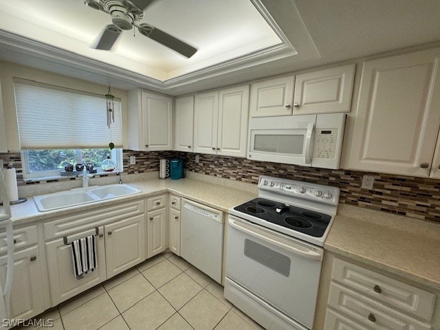 kitchen with white appliances, a raised ceiling, sink, light tile patterned floors, and white cabinetry