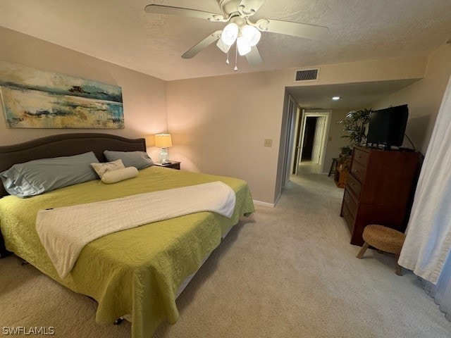 bedroom featuring ceiling fan, light carpet, and a textured ceiling