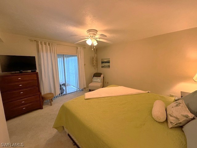 bedroom featuring a textured ceiling, ceiling fan, light carpet, and access to outside