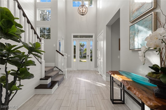 foyer entrance with a wealth of natural light, a high ceiling, and an inviting chandelier