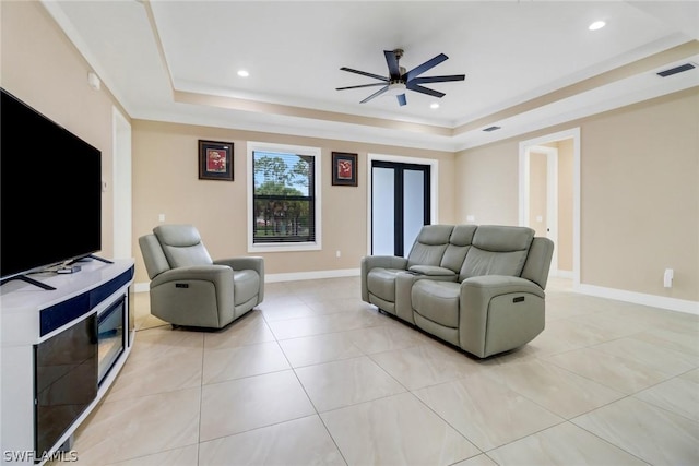 living room with light tile patterned floors, a raised ceiling, and ceiling fan