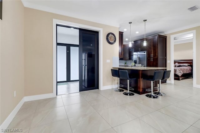 kitchen featuring a breakfast bar, hanging light fixtures, stainless steel refrigerator with ice dispenser, dark brown cabinetry, and kitchen peninsula