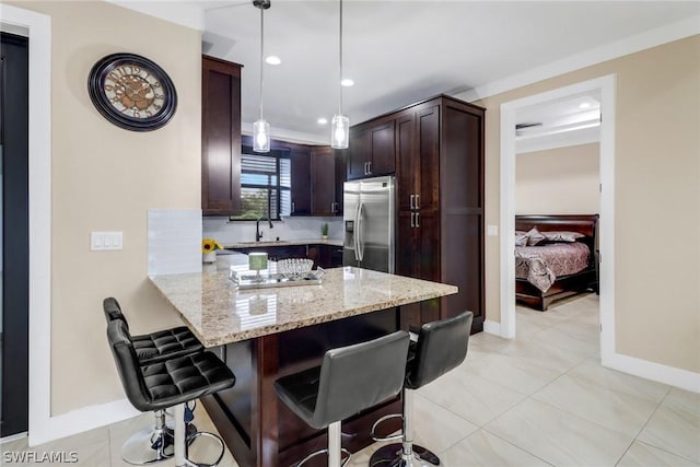 kitchen with stainless steel refrigerator with ice dispenser, a breakfast bar area, decorative light fixtures, kitchen peninsula, and light stone countertops