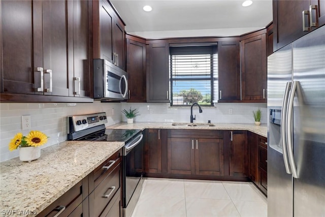 kitchen with light stone counters, sink, tasteful backsplash, and stainless steel appliances