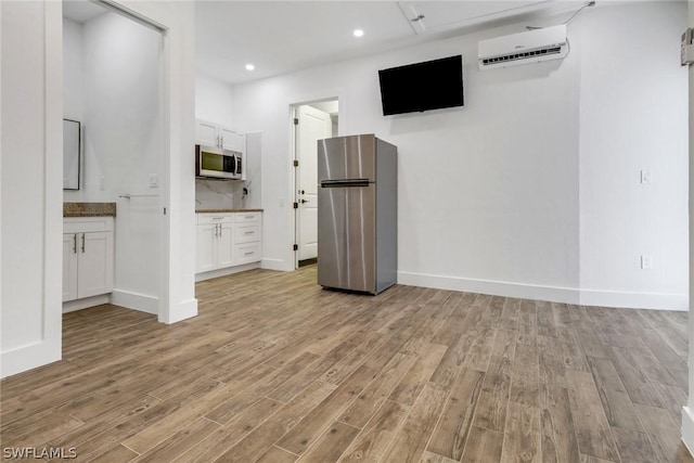 unfurnished living room featuring a wall mounted AC and light hardwood / wood-style flooring