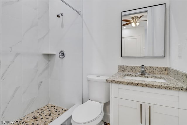 bathroom featuring ceiling fan, vanity, toilet, and a tile shower