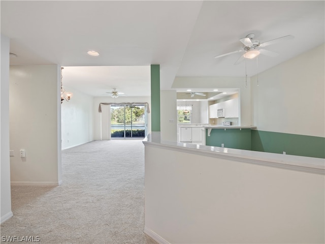 hallway with light carpet and a tray ceiling