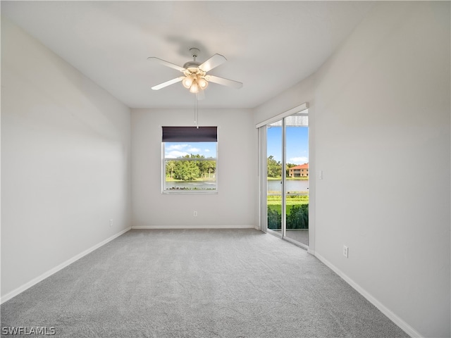 unfurnished room featuring carpet floors, ceiling fan, and a water view