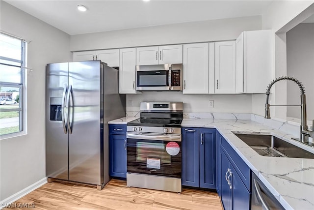 kitchen featuring light stone countertops, stainless steel appliances, white cabinetry, blue cabinets, and sink