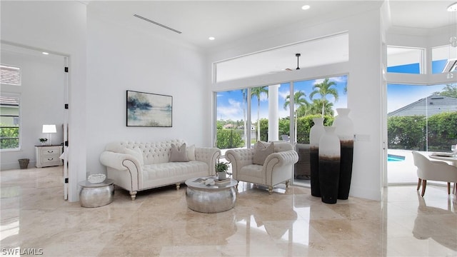 living room with ornamental molding, a wealth of natural light, marble finish floor, and a high ceiling