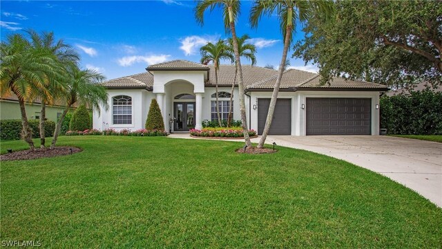 mediterranean / spanish-style home with a garage, french doors, and a front yard