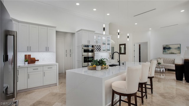 kitchen featuring stainless steel double oven, decorative backsplash, white cabinets, decorative light fixtures, and sink