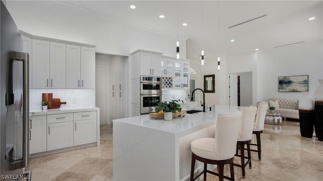 kitchen featuring double oven, a sink, white cabinetry, hanging light fixtures, and glass insert cabinets