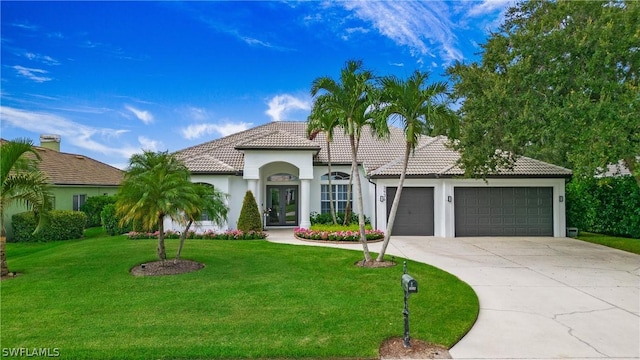 mediterranean / spanish-style home featuring french doors, a front lawn, and a garage