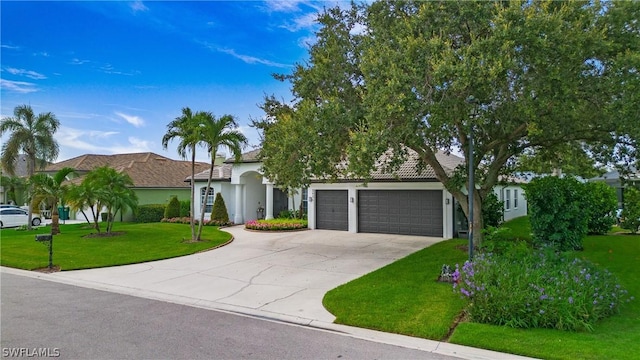 view of front of home featuring a garage, a tile roof, concrete driveway, stucco siding, and a front yard