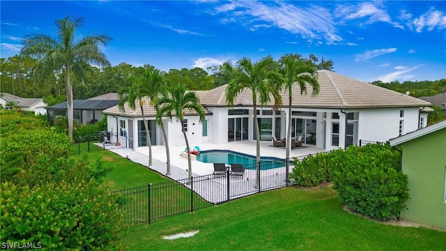 rear view of property with a yard, a fenced in pool, and a patio area