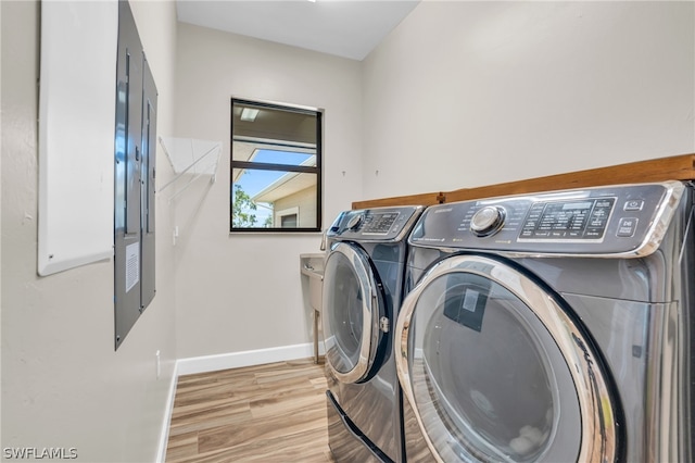 washroom with washing machine and clothes dryer and light wood-type flooring