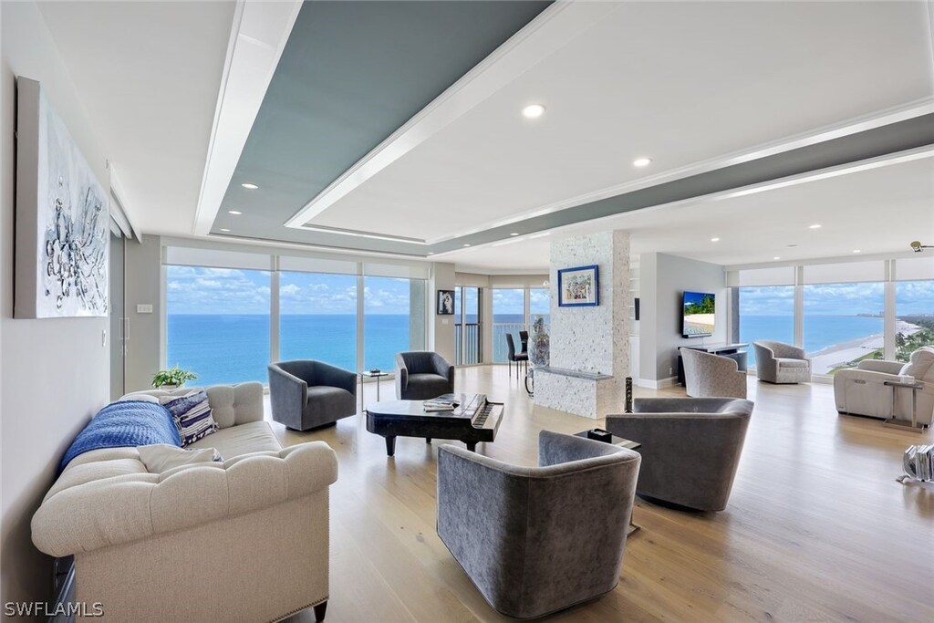 4051 Gulf Shore Blvd N Unit 1102, Naples, FL 34103 - living room with floor to ceiling windows, plenty of natural light, and light wood-type flooring