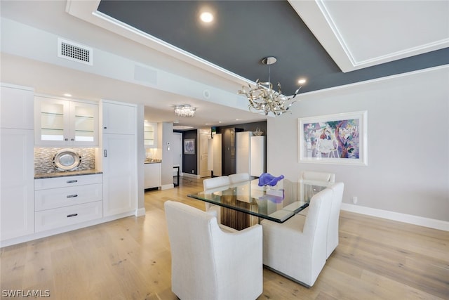 dining area with light hardwood / wood-style floors, ornamental molding, and a chandelier