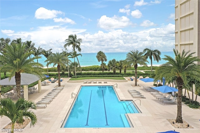 view of swimming pool featuring a water view and a patio