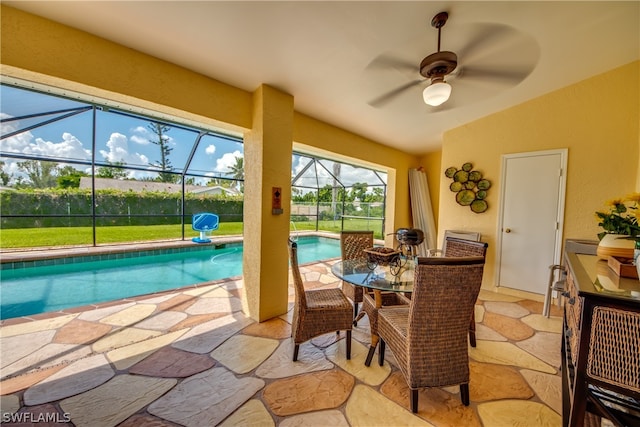 view of swimming pool with a yard, a patio, ceiling fan, and glass enclosure