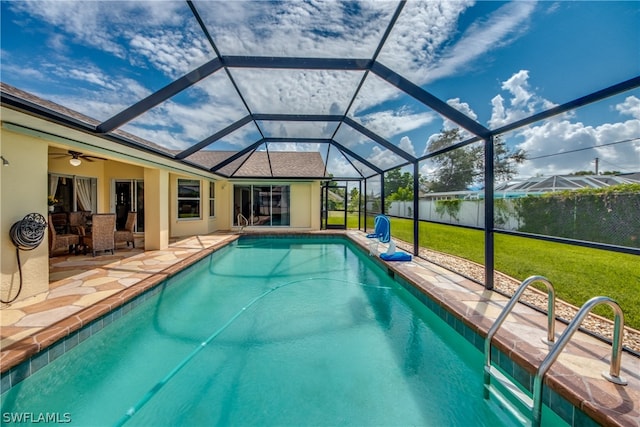 view of swimming pool featuring a patio, glass enclosure, a yard, and ceiling fan