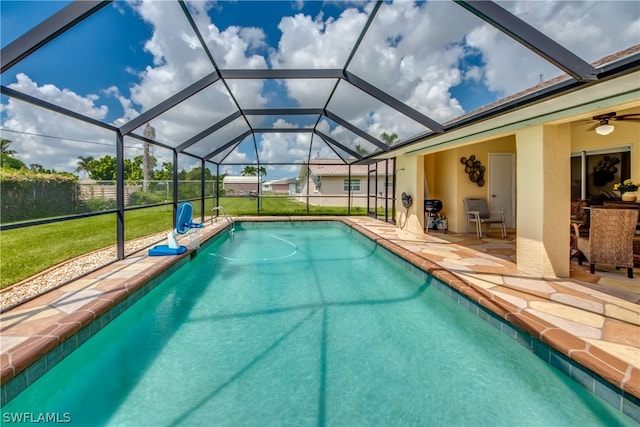 view of swimming pool featuring a lanai, a patio area, a yard, and ceiling fan